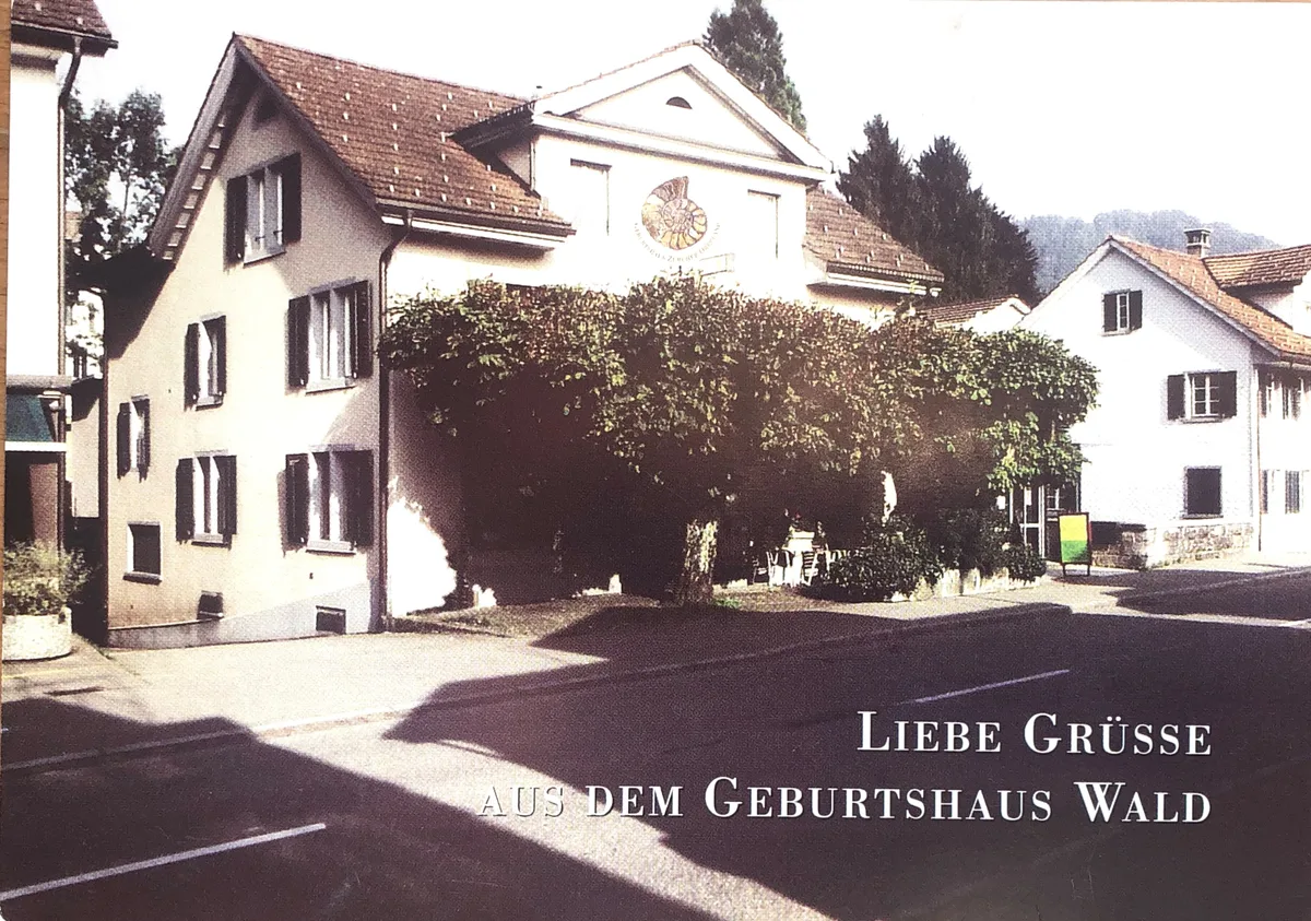 Eine Postkarte aus dem Jahr 1995 vom Geburtshaus Wald. Dieses war in einer ehemaligen Pilgerherberge stationiert. Man sieht ein Haus, darunter steht «Liebe Grüsse aus dem Geburtshaus Wald».
